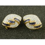 A pair of yellow metal, diamond, and sapphire earrings of curved lozenge form.