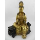 A Chinese bronze figural study of Guanyin sitting on a dog of Fo. H.