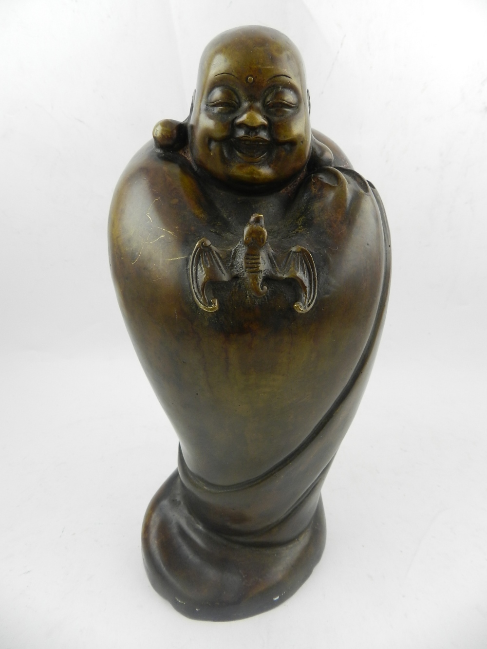A Chinese bronze figural study of a Buddha in a cape, having mounted bat,