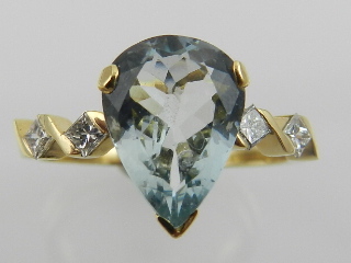 A gold, platinum, diamond and aquamarine set ring, the central pear cut aquamarine flanked by four