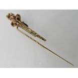 A yellow metal tie pin designed as a boutonniere of roses.