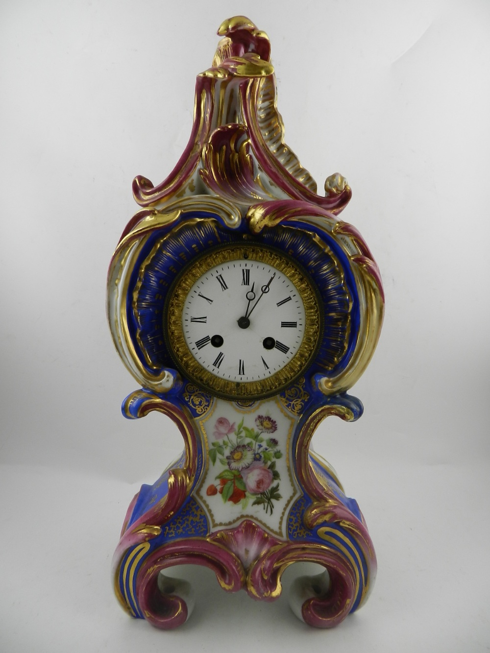 A Continental porcelain mantle clock, of blue and pink, decorated with flowers, having a Roman dial.