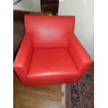 A pair of 1920s style reading chairs, having crimson red faux leather upholstery, raised on