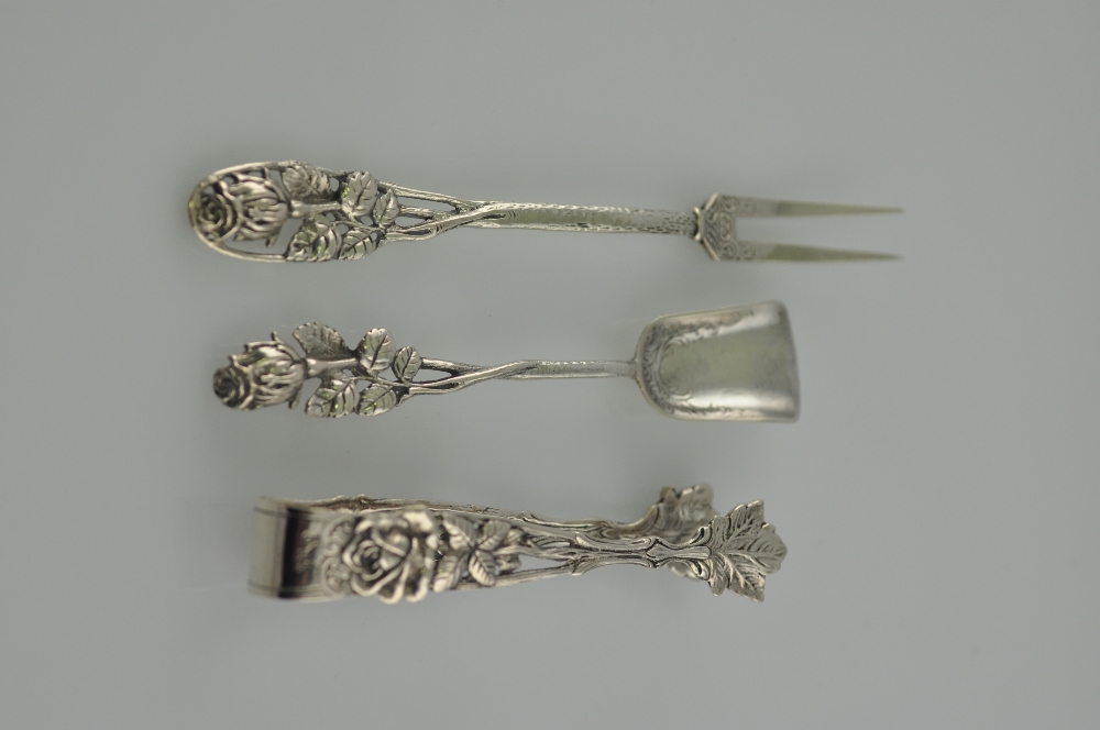 A pair of white metal sugar tongs, pierced and decorated with roses and beads, and stamped 800,