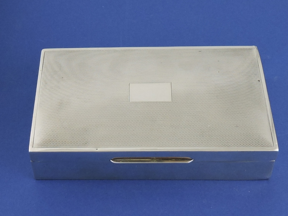 A silver rectangular cigarette box, Birmingham 1956, with engine-turned lid, W. 15cm.