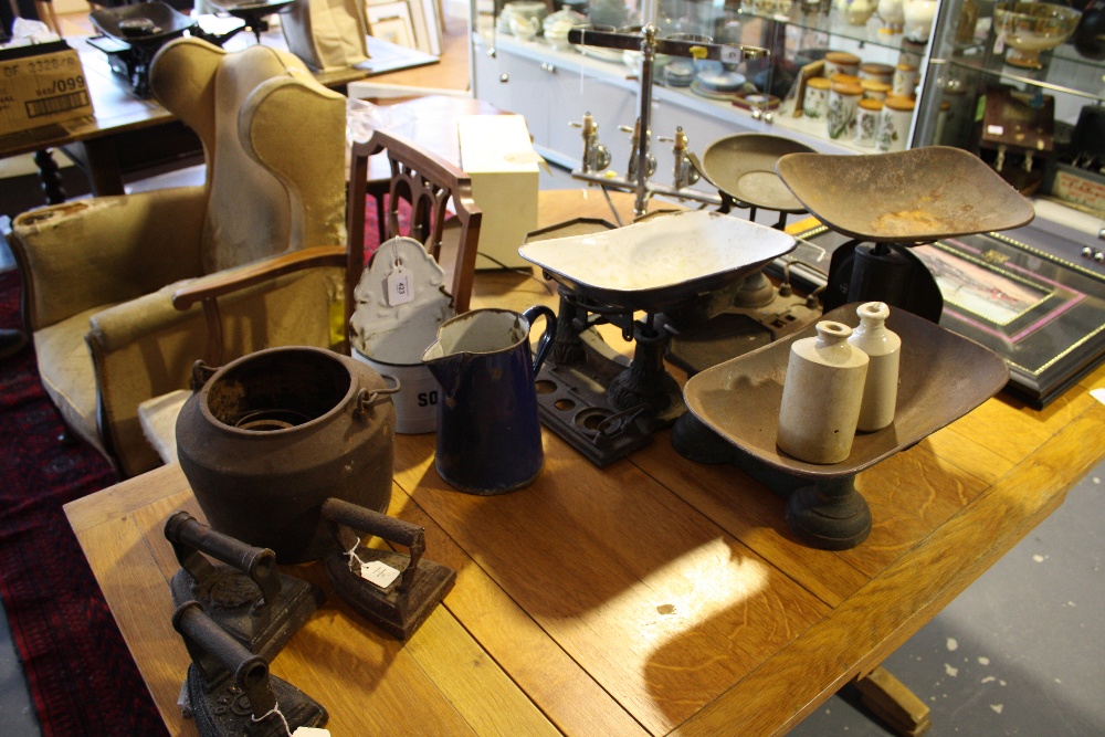 A collection of enamel and cast iron kitchenalia including soda jar, flat irons, and scales.