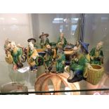 A collection of fourteen Tang style pottery figure groups, in blue, green and yellow glazes,