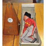 A prim walnut cased metronome together with a boxed Asian girl pelham puppet.