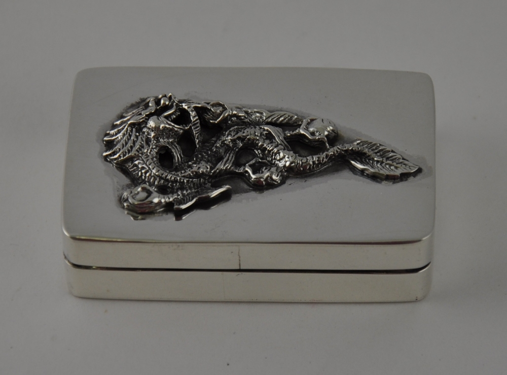 A rectangular silver pillbox, the detachable cover cast with a sacred dragon, 5.5cm.