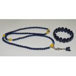 A lapis lazuli necklace of uniform beads, together with a similar bracelet of oval beads.