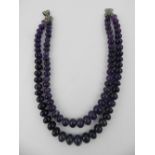 A double strand necklace of smooth amethyst beads, with a white metal clasp.