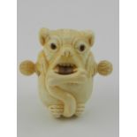 A novelty carved bone tape measure in the form of a bulldog with a bone in his mouth.