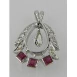 A white metal, diamond, and ruby pendant, suspended a pear cut diamond.