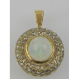 A yellow metal, opal, and diamond set circular pendant.