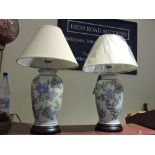 A pair of Chinese style blue and white pottery tablelamps with natural fabric shades.