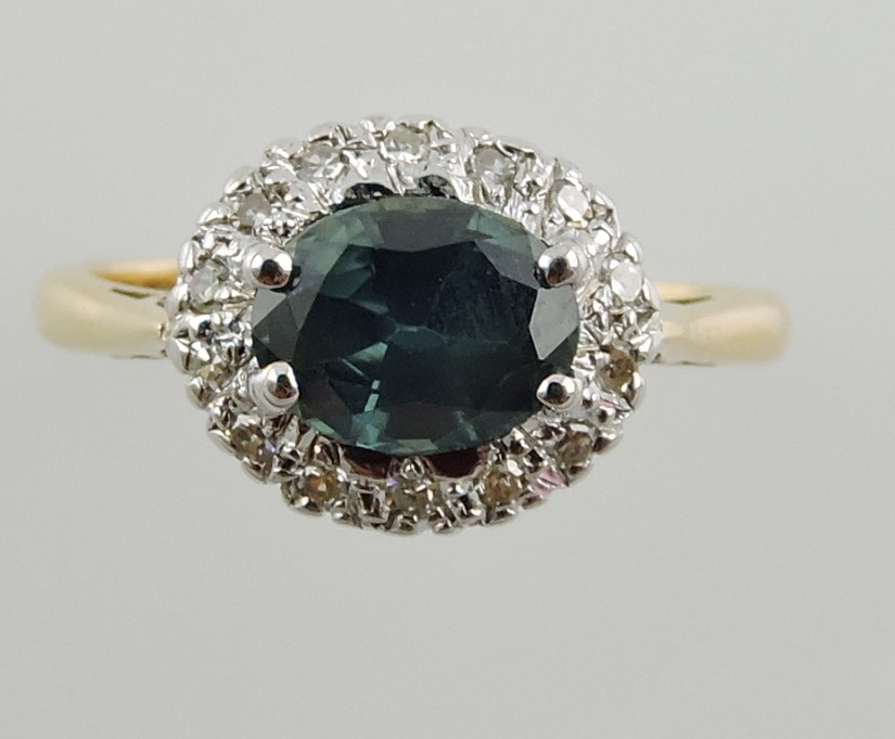 A green sapphire and diamond cluster ring, set in a yellow metal band, 3.5g.