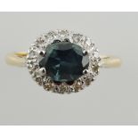 A green sapphire and diamond cluster ring, set in a yellow metal band, 3.5g.