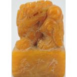 An amber soapstone seal, square carved in the form of a dragon, H. 7cm..