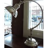 A plated desk lamp with circular shade on curved arm and stepped base.