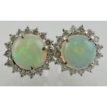 A pair of opal and diamond set ear studs, circular cabouchon central stone,