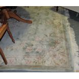 A Chinese pale green ground carpet embossed with a central floral medallion within a wide border,