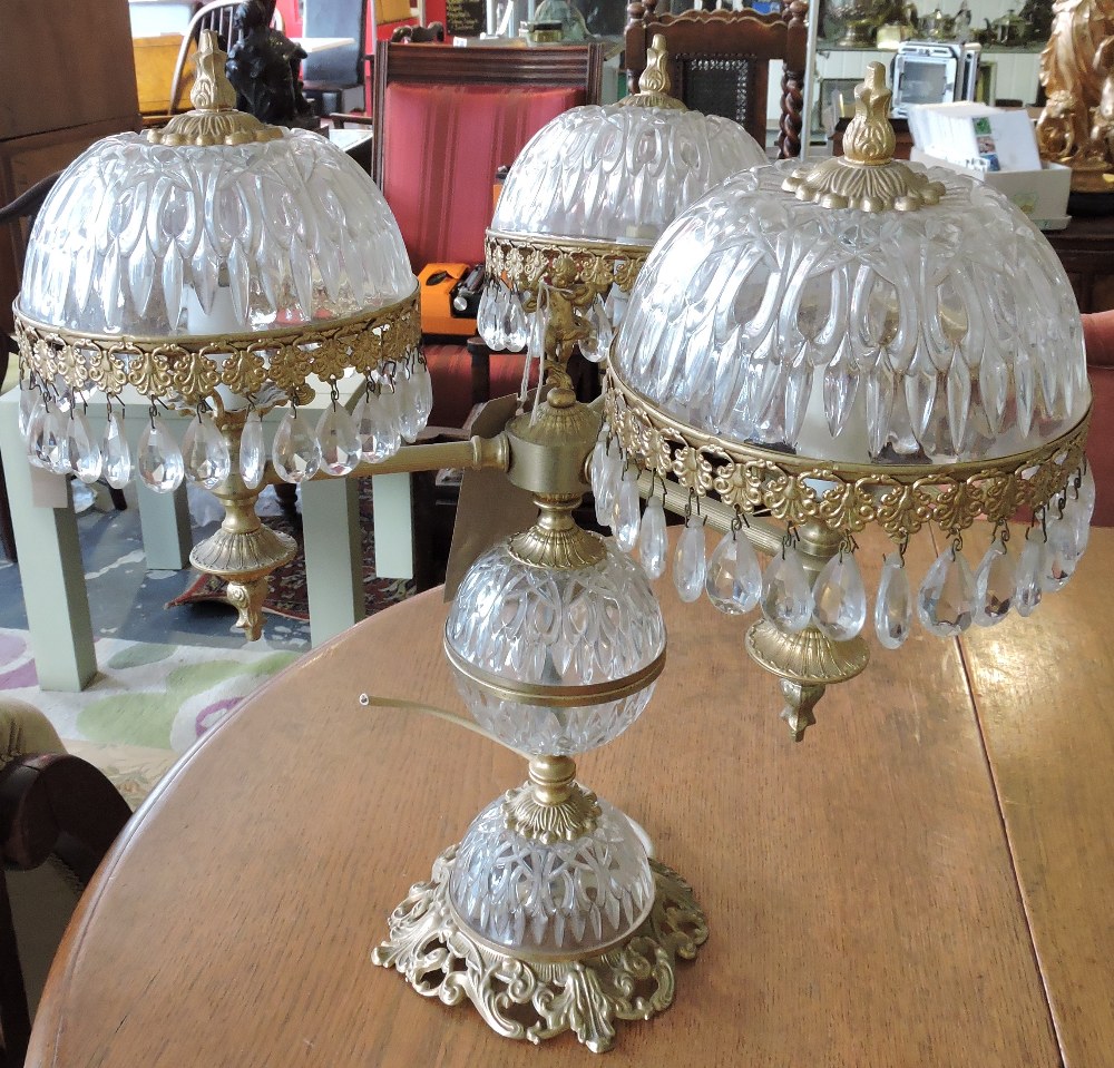 A gilt metal and moulded glass three branch tablelamp, the domed shades hung pear shaped drops.