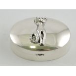 An oval silver pillbox, the domed cover applied with a stylised seated cat.