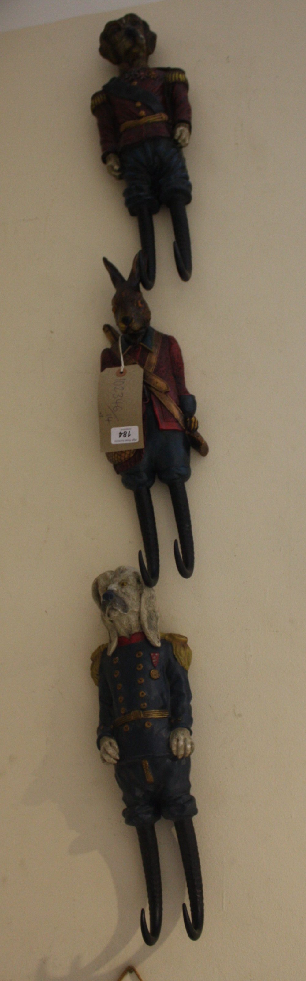 A set of three Austrian style composition coat hooks medelled as dog generals and hare gamekeeper,