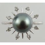 A black pearl and diamond set dress ring, with a sunburst setting on a white metal band stamped 375.