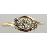 A three stone cross-over diamond dress ring, graduated stones within a collet setting,