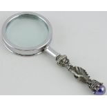 A plate mounted and chrome magnifying glass, the handle cast as clasped hands.