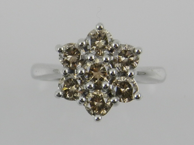 An 18 carat white gold and diamond flower cluster ring, set with seven matching champagne