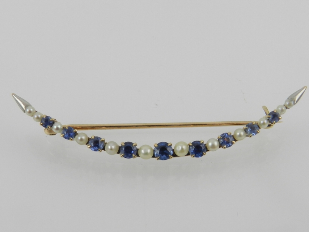 A yellow metal, sapphire and diamond set crescent brooch, the mount stamped 14K.
