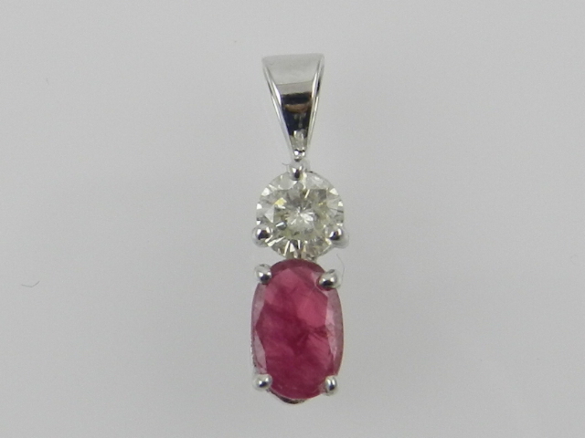 An 18 carat white gold, diamond, and ruby pendant, the oval cut ruby of approx. 0.45 carats, above a