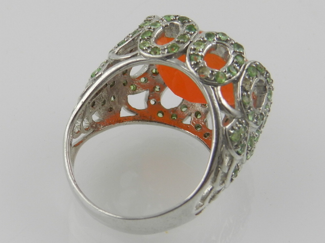 A white metal cocktail ring, set with a large carnelian, the mount set with small green stones. - Image 2 of 2