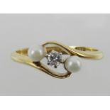 An 18 carat yellow gold crossover-style ring, set single diamond flanked by two small pearls.