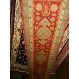 A red ground Kazak runner, having three medallions to centre on a geometric floral ground, multi-