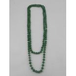 An opera length necklace of green jadeite beads.