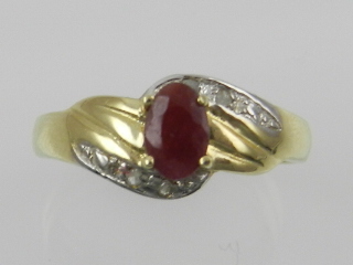 A yellow metal and ruby ring, the shoulders set with diamond accents, the shank stamped 375.
