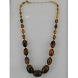 A yellow metal and simulated amber necklace of graduated beads.