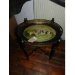 A Victorian oval toleware tea tray, depicting Staffordshire dogs, raised on ebonised stand.