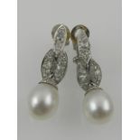 A fine pair of white metal, diamond, and pearl drop earrings.