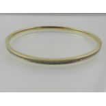 A 9 carat yellow gold bangle, set all round with small diamonds.