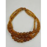 A triple strand synthetic amber necklace, with a white metal mounted clasp.