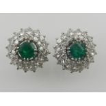 A pair of white gold, emerald, and diamond cluster ear studs.