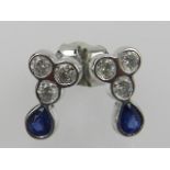 A pair of 18 carat white gold, diamond, and sapphire earrings, each set three round cut diamonds