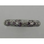 An unusual white metal, and purple and white diamond set half eternity ring.