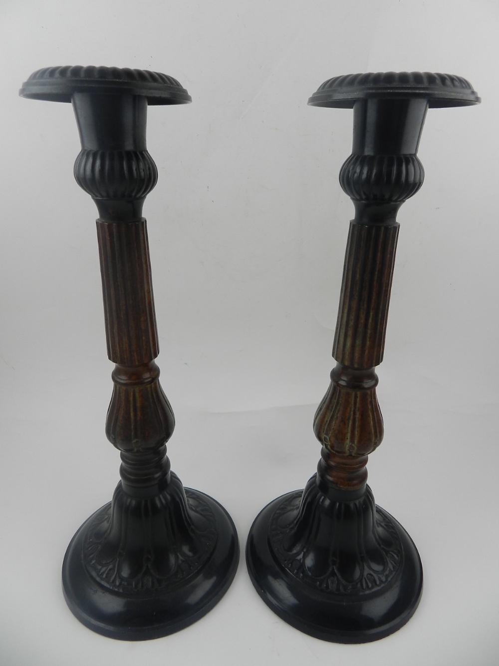 A pair of metal candlesticks, having reeded stems. H.