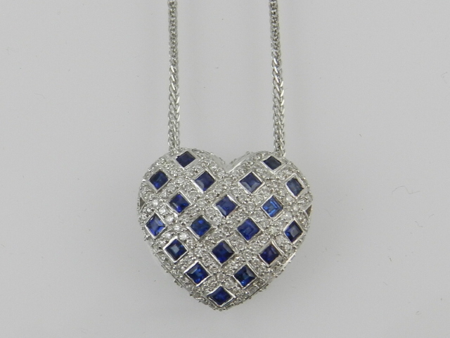 An 18 carat white gold, diamond and sapphire set heart-shaped pendant of lattice design, suspended