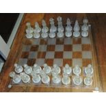 A 20th century glass chess set, the sides of clear and frosted glass, board W. 35cm.